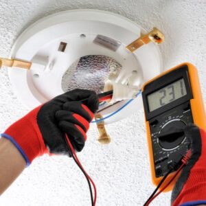 An electrician testing a ceiling light fixture with a multimeter for Illiana Electrical in Whiting, IN