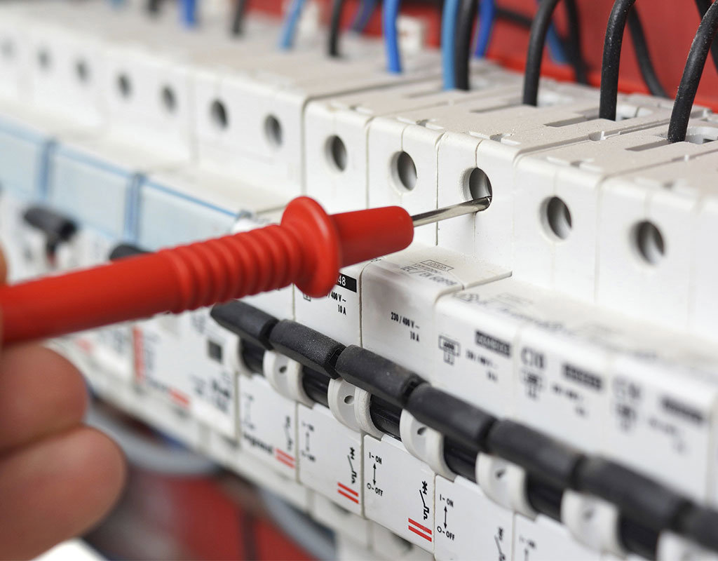 An electrician testing circuit breakers in an electrical panel for Mulholland Electric Inc in San Francisco, CA.