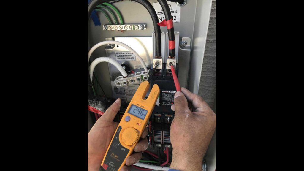 An electrician from Eco Electric testing electrical connections inside a panel with a clamp meter in Las Vegas, NV.