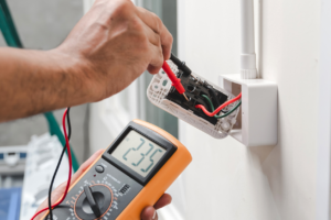 An electrician testing an electrical outlet with a multimeter for True Light Electric in Albuquerque, NM.