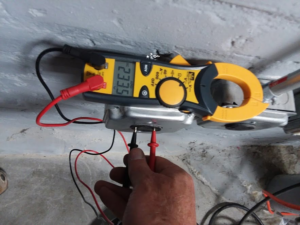 An electrician using a multimeter and clamp meter to test an electrical outlet for Wilderness Electric in Grand Rapids, MI
