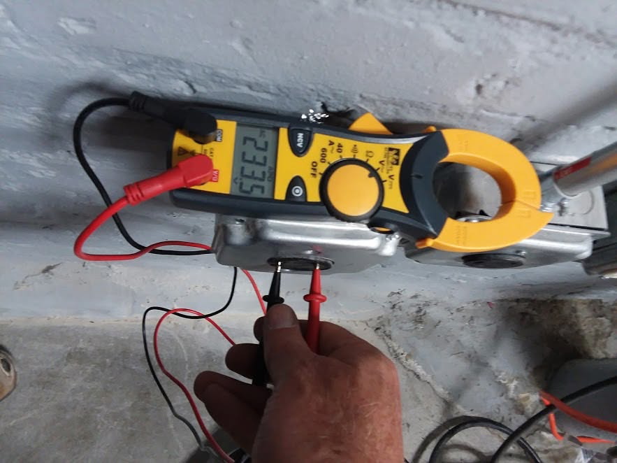 An electrician using a multimeter and clamp meter to test an electrical outlet for Wilderness Electric in Grand Rapids, MI