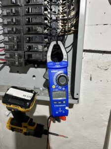 An electrician using a clamp meter to test an electrical panel, performing diagnostics for Buckeye Electric of Upper Arlington, LLC in Columbus, OH.