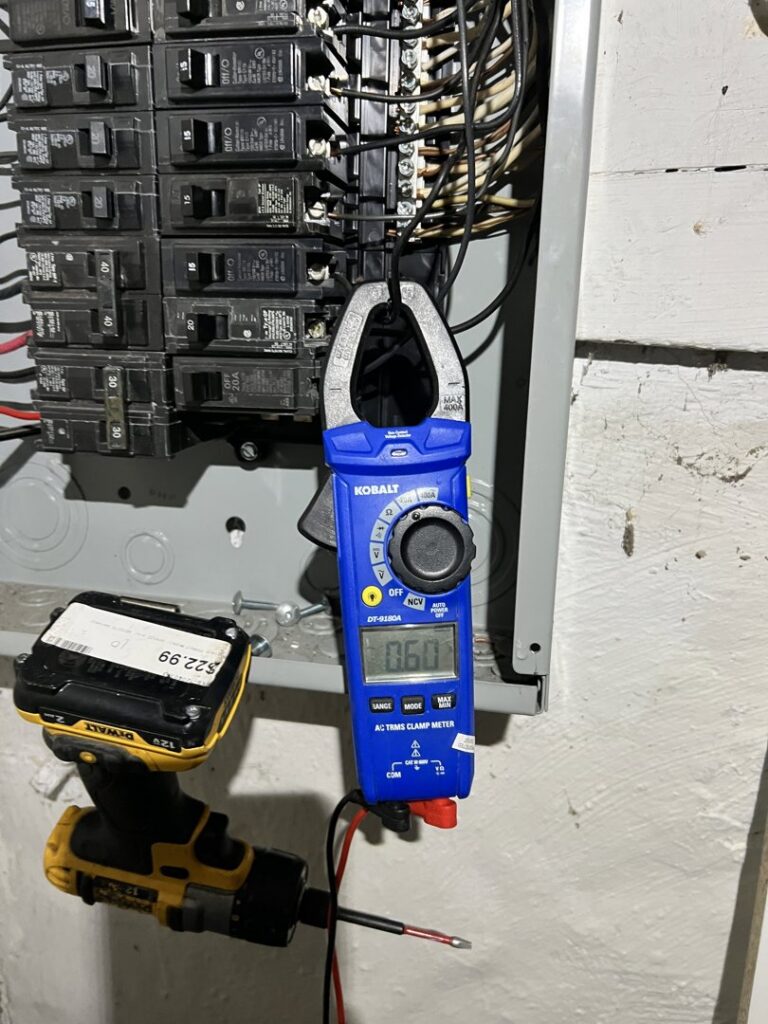 An electrician using a clamp meter to test an electrical panel, performing diagnostics for Buckeye Electric of Upper Arlington, LLC in Columbus, OH.