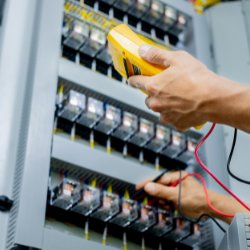 An electrician using a multimeter to test an electrical panel or circuit board for D. Geer Electric Inc. in Waukegan, IL.