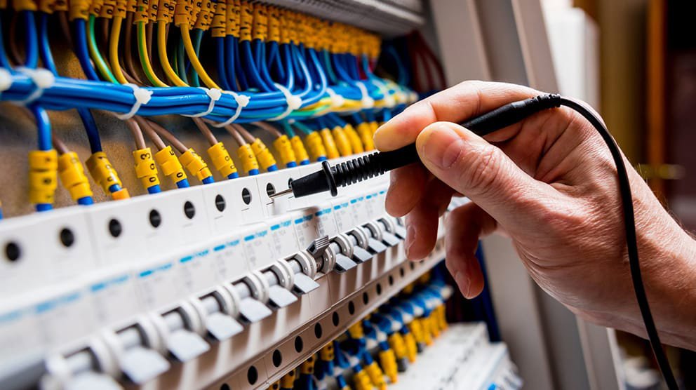 An electrician using a multimeter to test connections within an electrical panel, ensuring safety and functionality for Devaney Electric Co. in Lacey, WA.