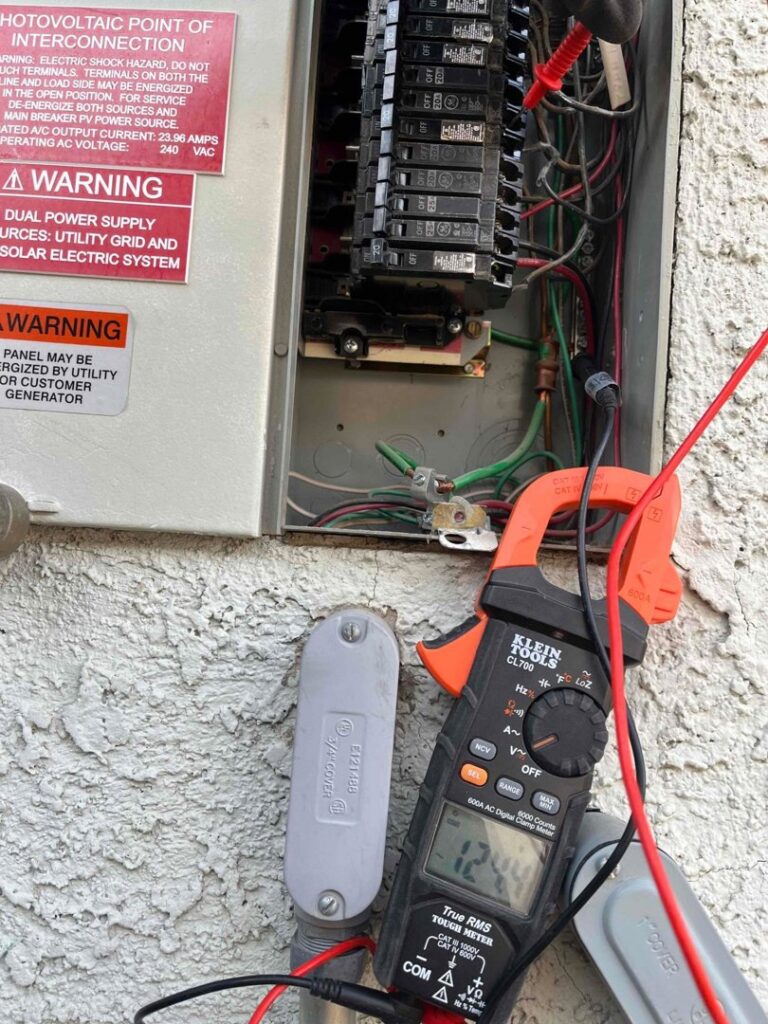 An electrician from Eco Electric testing an electrical panel with a clamp meter in Las Vegas, NV.