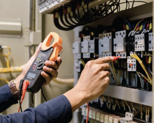 An electrician testing an electrical control panel with a multimeter for Grassland Electric in Franklin, TN.