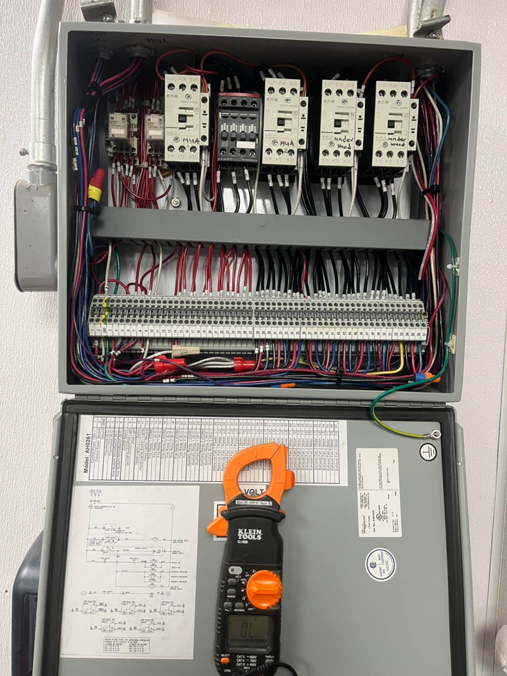 An electrician using a multimeter to test an open electrical panel, performed by JJRS Electrical, LLC in Colorado Springs, CO.