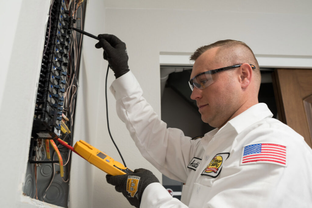 An electrician from Mister Sparky Kansas City, MO, testing an electrical panel with a multimeter.