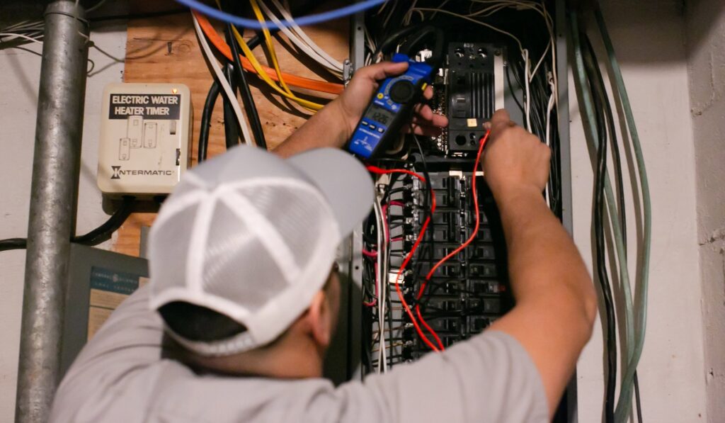 An electrician from Revamp Athens Electrical Company testing an electrical panel with a multimeter in Athens, GA.