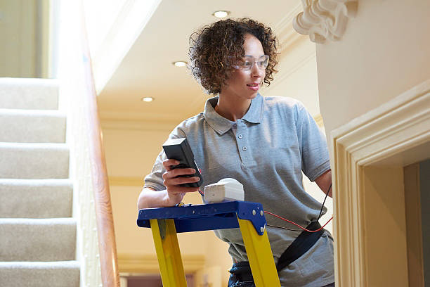 An electrician using a testing device on a ladder for Crawford Electric Co. LLC in West Columbia, SC.