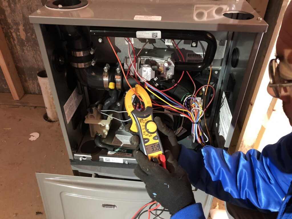 An electrician from Barrios Electric LLC testing furnace wiring with a clamp meter in Norwalk, CT.