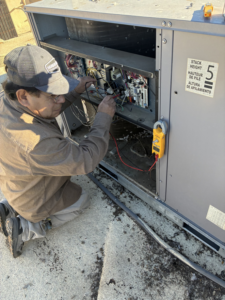 An electrician testing wiring inside an HVAC unit with a multimeter for Cool Aid Air Conditioning in Scottsdale, AZ.