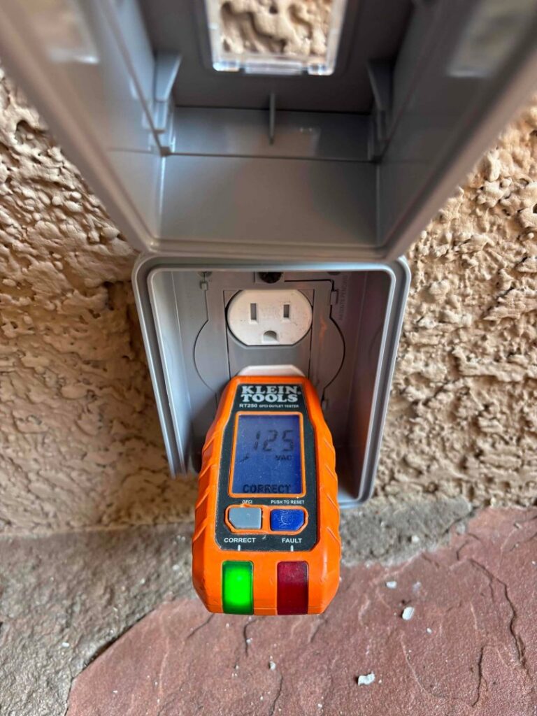 An electrician from Eco Electric testing an outdoor electrical outlet with a Klein Tools tester in Las Vegas, NV.