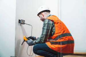 An electrician from EMS Electric of Monroe LLC testing an electrical outlet with a multimeter in Monroe, LA.