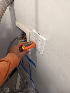 An electrician's hand using an electrical tester on an outlet, demonstrating diagnostic work by Primo's Electrical Services in San Diego, CA.