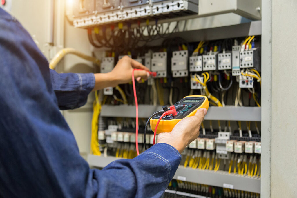 An electrician using a multimeter to test connections in an electrical panel, a service by Beaver Electric in Hillsboro, OR.