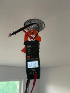 An electrician testing voltage in a ceiling electrical box with a multimeter for Rogers Family Handyman in Chandler, AZ
