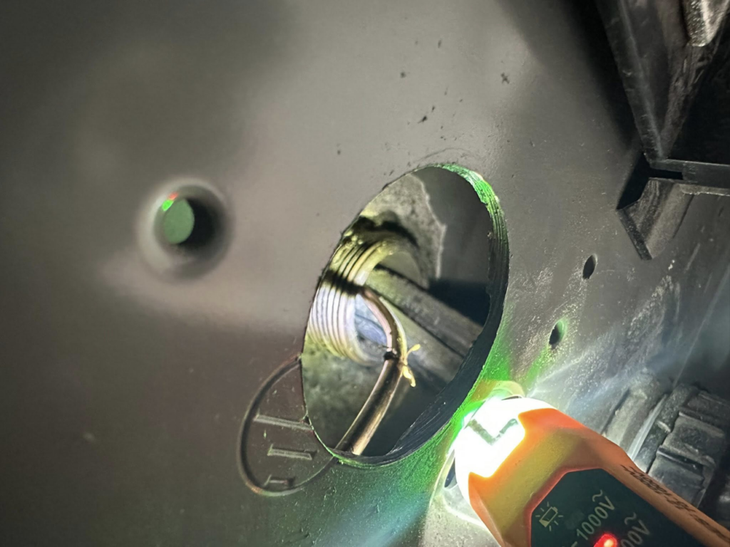 An electrician using a non-contact voltage tester on wires inside a conduit, performed by Watts Happening Electric in Lakewood, CO.