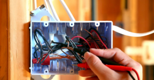 An electrician testing wires in an electrical box with a multimeter for Lightningwerks Electrical in Springfield, MO.