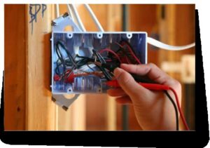 An electrician testing wires in a junction box with a multimeter, performed by Phoenix Electric, Inc. in Cape Coral, FL