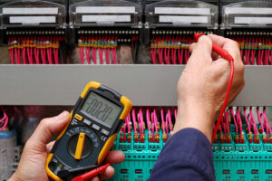 An electrician testing electrical wiring with a multimeter at Mulholland Electric Inc in San Francisco, CA.