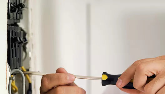 A close-up view of an electrician's hands using a screwdriver to tighten an electrical component, showcasing the detailed work by Legacy Electric in Westminster, CO.