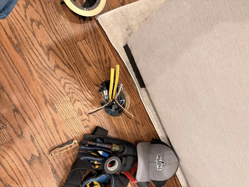 Electrician tools and wires on a wooden floor during a floor outlet installation by Balderas Electric in Austin, TX.