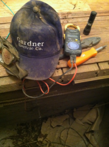 Electrician's tools including a multimeter, pliers, and a Gordon Gardner Electric hat on a job site in Los Angeles, CA.