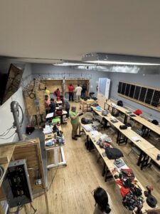 An overhead view of an electrician training workshop with students working on electrical and solar panels at Escuela Tecnica ABC in North Chicago, IL