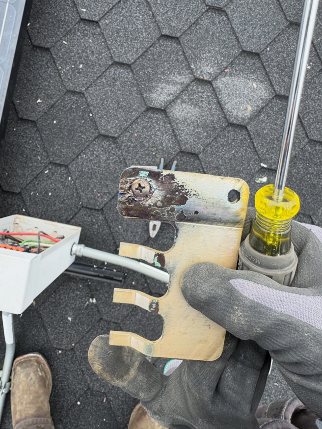 An electrician's gloved hand using a screwdriver on an electrical component on a roof for Garcia Electric Services in Bonita, CA.