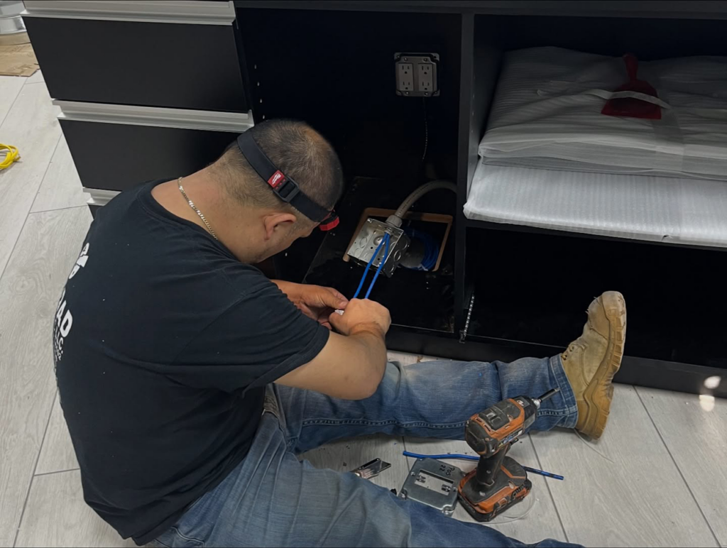 An electrician performing wiring for a cabinet installation at a client's location by Haddad Electric LLC in Jersey City, NJ.