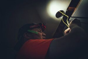An electrician installing or repairing ceiling wiring with a headlamp for Alyeska Electric in Anchorage, AK.