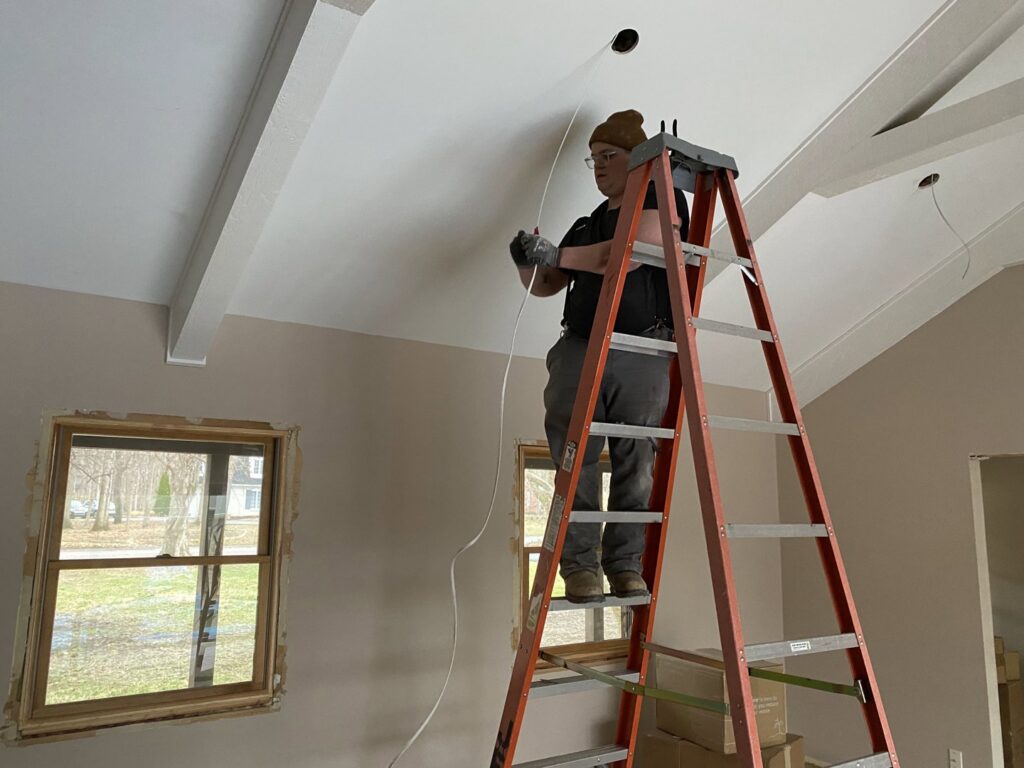 An electrician from Zimmerman Electric Indy pulling wires for new ceiling lights during an installation in Indianapolis, IN