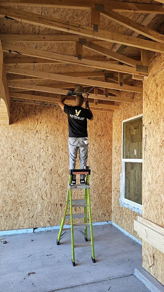 An electrician from V Electrical LLC wiring a ceiling in a new construction project in Albuquerque, NM.