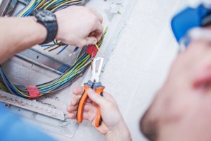 An electrician from EMS Electric of Monroe LLC wiring an electrical box with colorful wires in Monroe, LA.