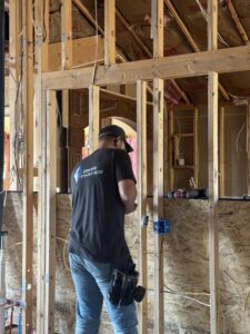An electrician from P.H. Electric performing wiring work inside a framed wall in Soulsbyville, CA.