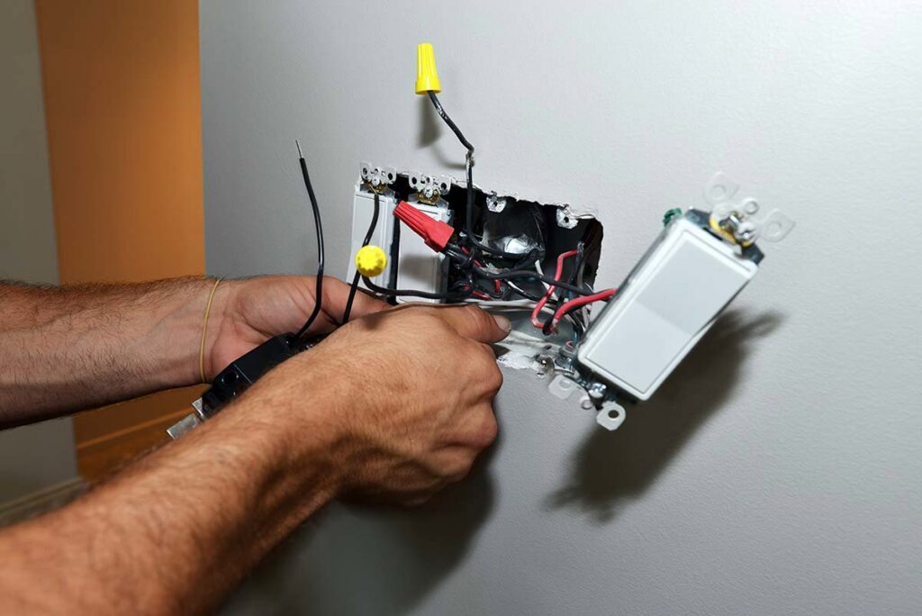 An electrician wiring a new light switch and outlet for T-Volt, Inc. Electrical Contractor in Fort Lauderdale, FL.