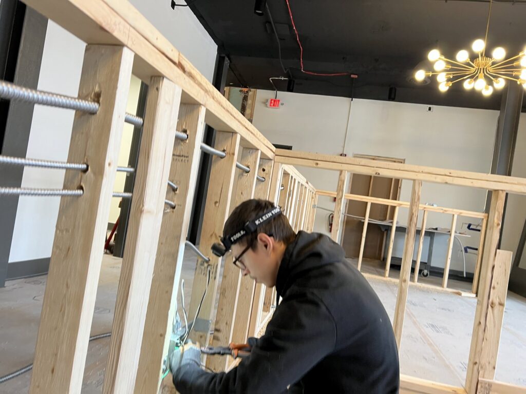 An electrician installing wiring inside a wooden wall frame during new construction for Buckeye Electric of Upper Arlington, LLC in Columbus, OH.