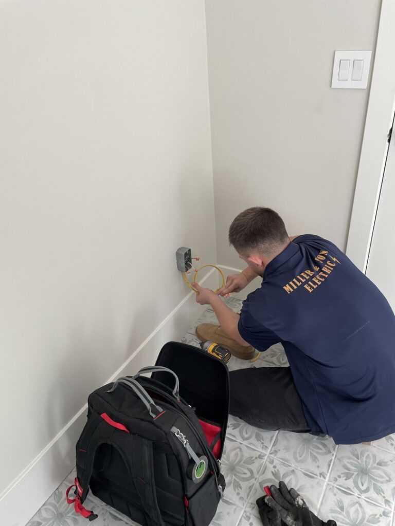 An electrician performing wiring for an outlet installation in a wall for Miller and Sons Electric in North Myrtle Beach, SC.