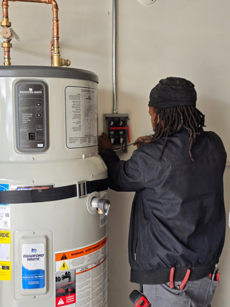 An electrician performing wiring work on a water heater, showcasing expertise from Muse Electricians in Los Angeles, CA.