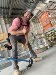 An electrician from Stroh Electrical holding a conduit bender and level at a construction site in Montgomery, AL.