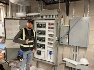 An electrician from Master Controls giving a thumbs up next to an open electrical control panel in Cheyenne, WY