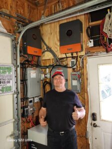 An electrician from Henelect Electrical Contractors proudly showing a completed solar inverter installation in Milford, NJ.