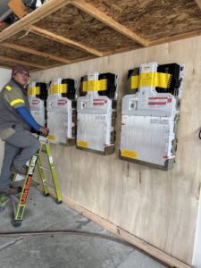 An electrician standing next to a newly installed solar inverter system by Pioneer Electric LLC in West Valley City, UT.