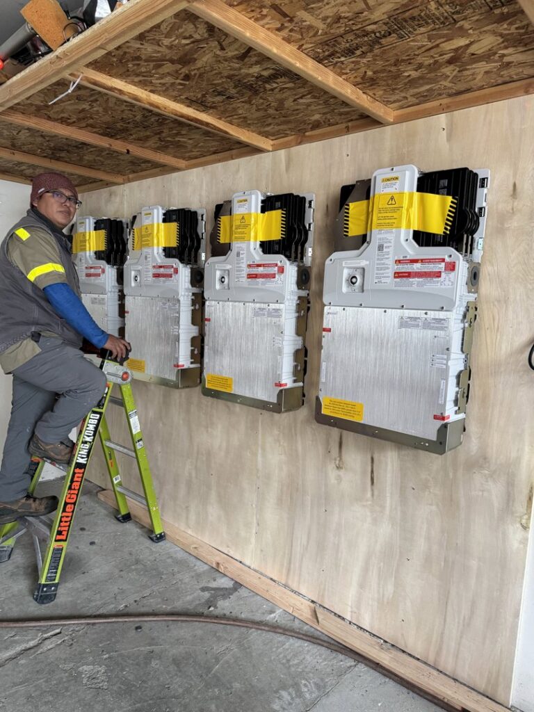 An electrician standing next to a newly installed solar inverter system by Pioneer Electric LLC in West Valley City, UT.