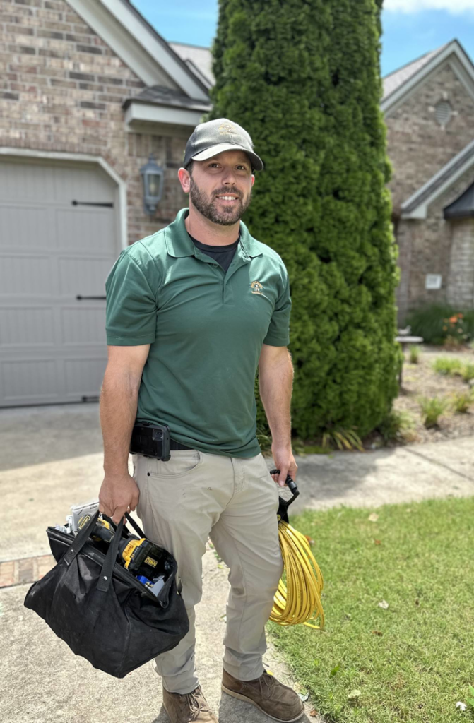 An electrician from Whitmer Electric carrying tools and electrical cable outside a home in Rogers, AR.