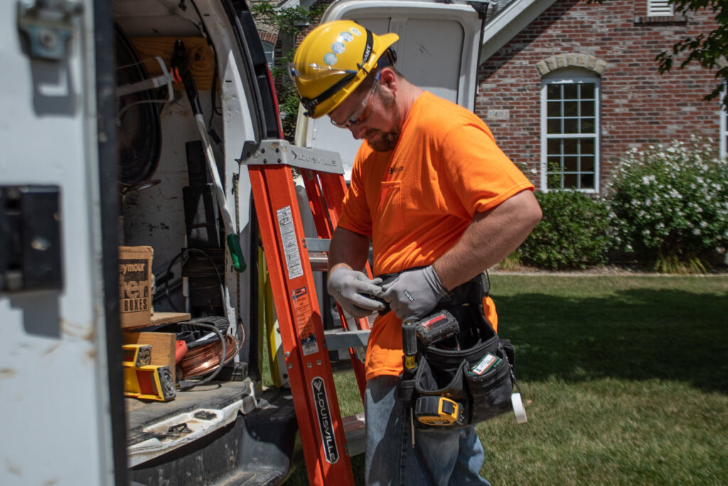 An electrician wearing a hard hat and tool belt, standing by a work van, ready for a job with J. Bathe Electric in Saint Charles, MO.