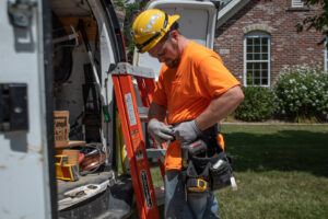 An electrician wearing a hard hat and tool belt, standing by a work van, ready for a job with J. Bathe Electric in Saint Charles, MO.